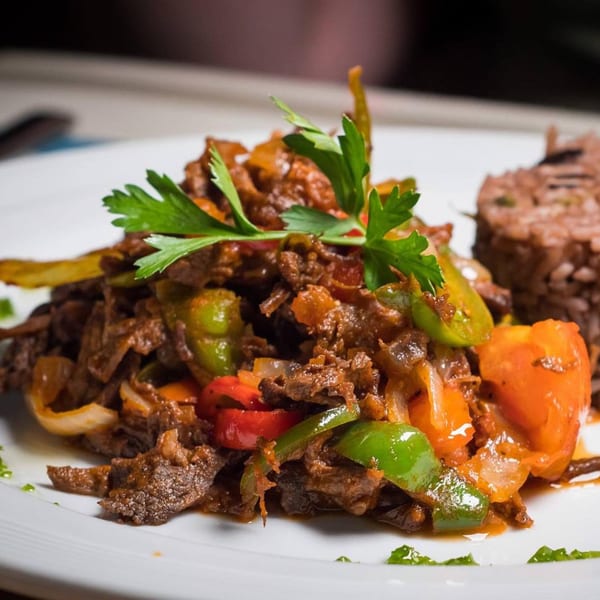 Cuban shredded beef with peppers and onions, garnished with parsley, served with rice.